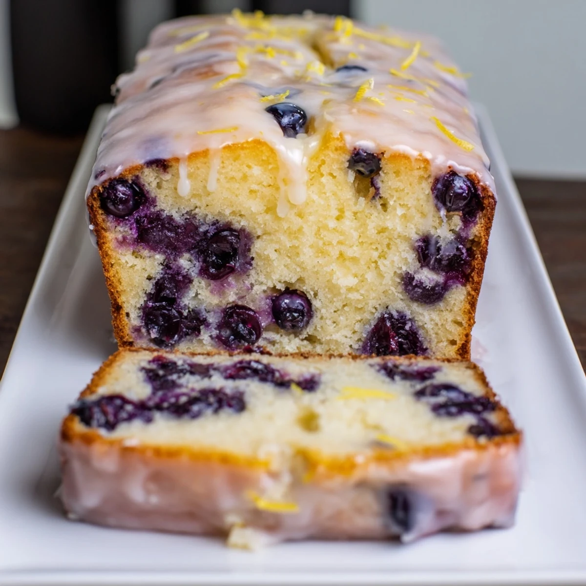 Fluffy Lemon Blueberry Yogurt Loaf, drizzled with lemon glaze, ready for a delicious dessert.