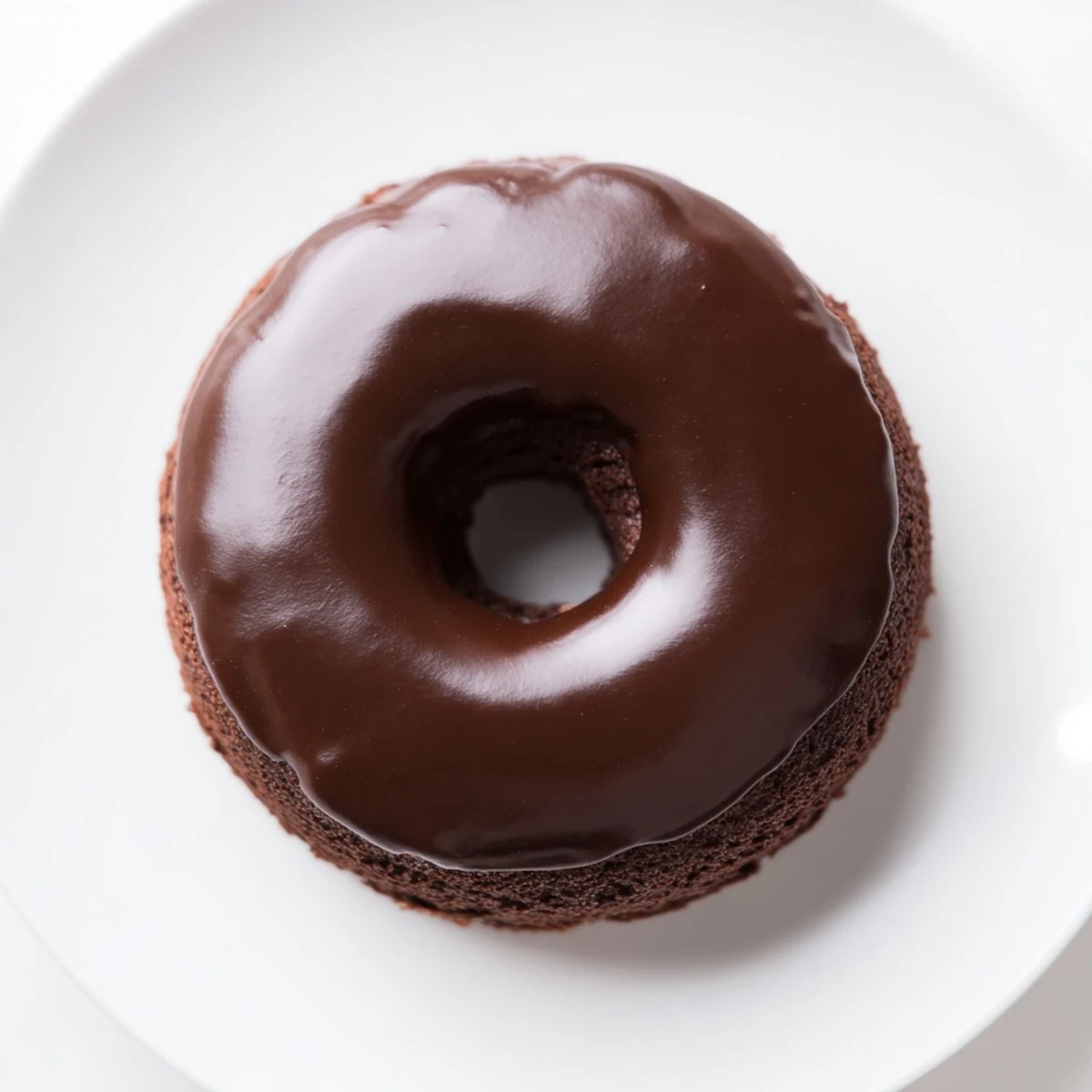 A glistening chocolate donut, boasting a decadent glaze, ready for a comforting bite.