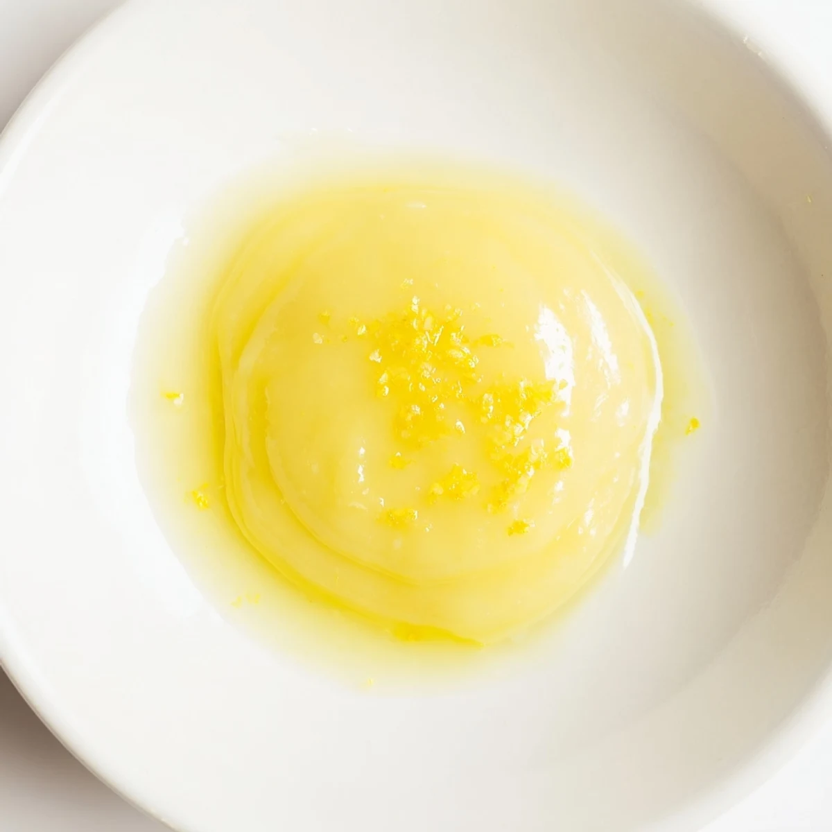 Bright yellow lemon curd, with a smooth, luxurious texture, ready to fill a cake layer.