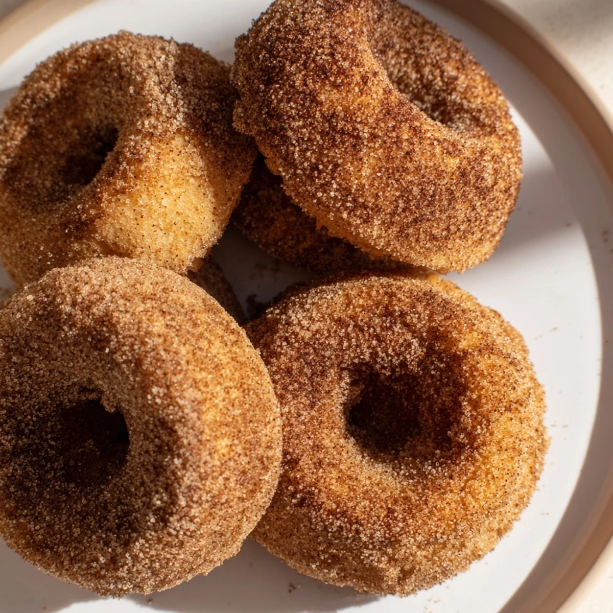 Warm apple cider donuts, fresh from the oven, coated in cinnamon sugar, a perfect fall treat.