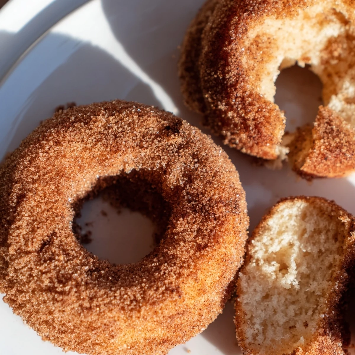 Moist, cake-like apple cider donuts glistening with melted butter and a sweet, spiced coating.
