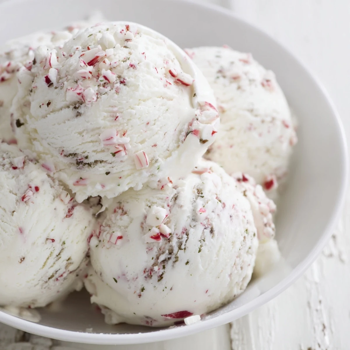 Homemade Peppermint Ice Cream overflowing with crushed candy canes, ready for a scoop.