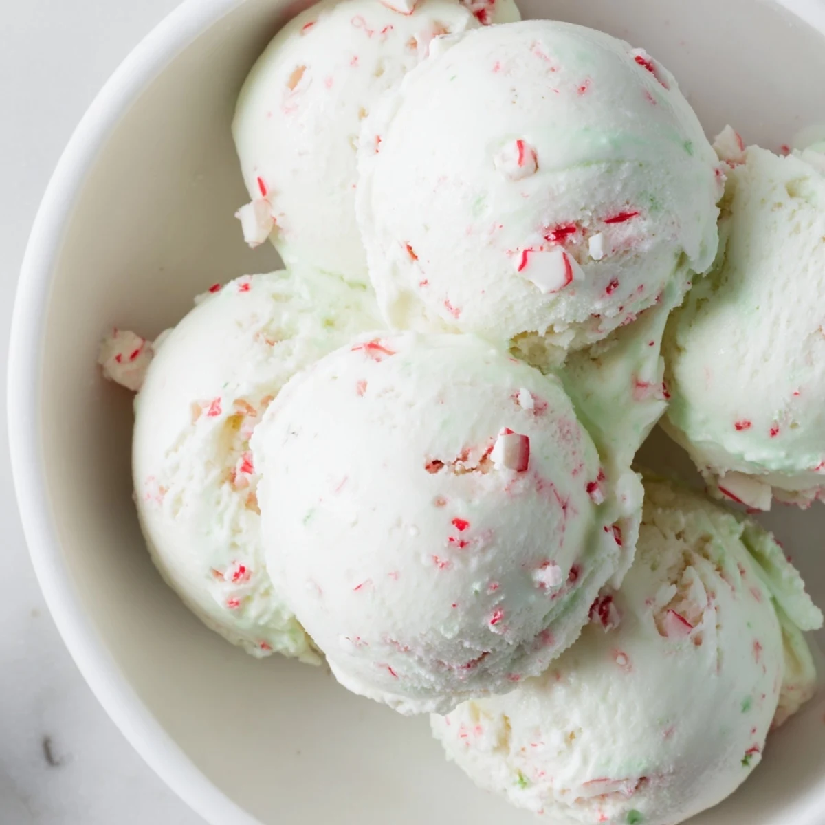 A chilled bowl of creamy, homemade Peppermint Ice Cream, flecked with bright peppermint pieces.