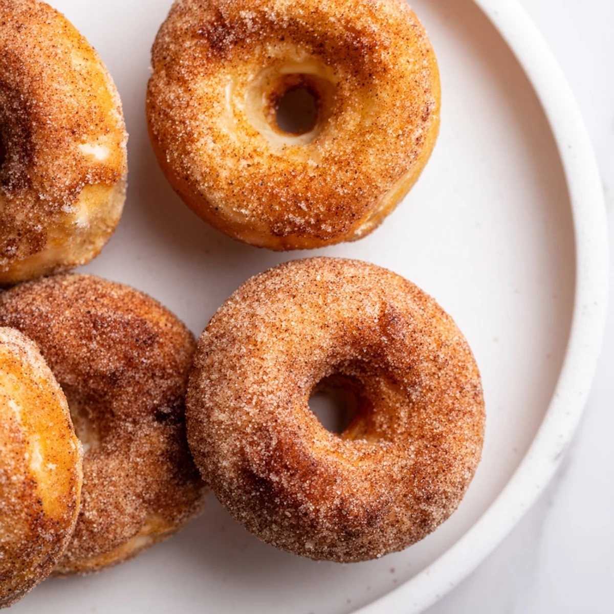 A pile of fluffy cinnamon sugar donuts, perfect for a cozy breakfast alongside hot coffee.