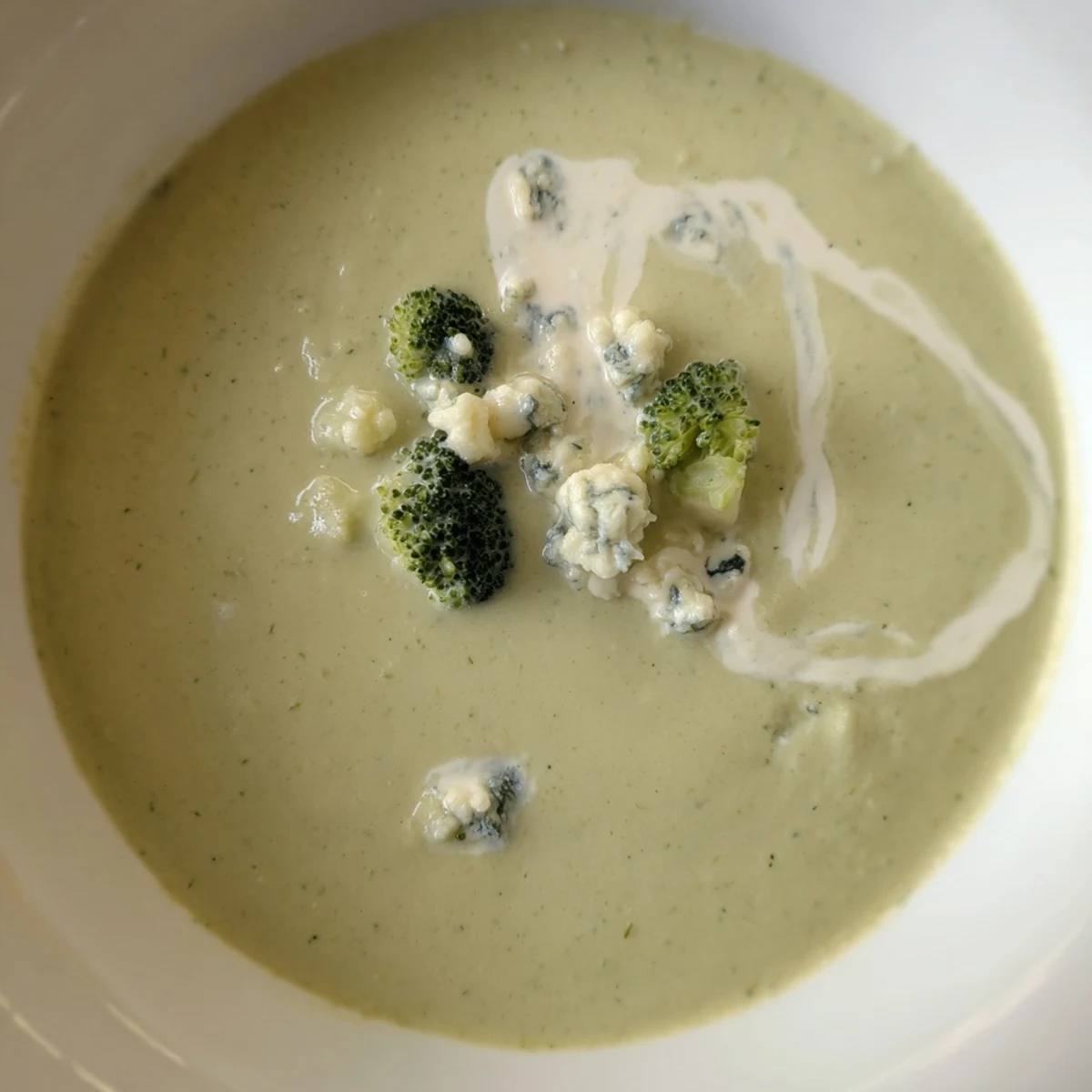 Rich and smooth Creamy Broccoli and Stilton Soup, a vegetarian delight, is ready to be enjoyed with bread.