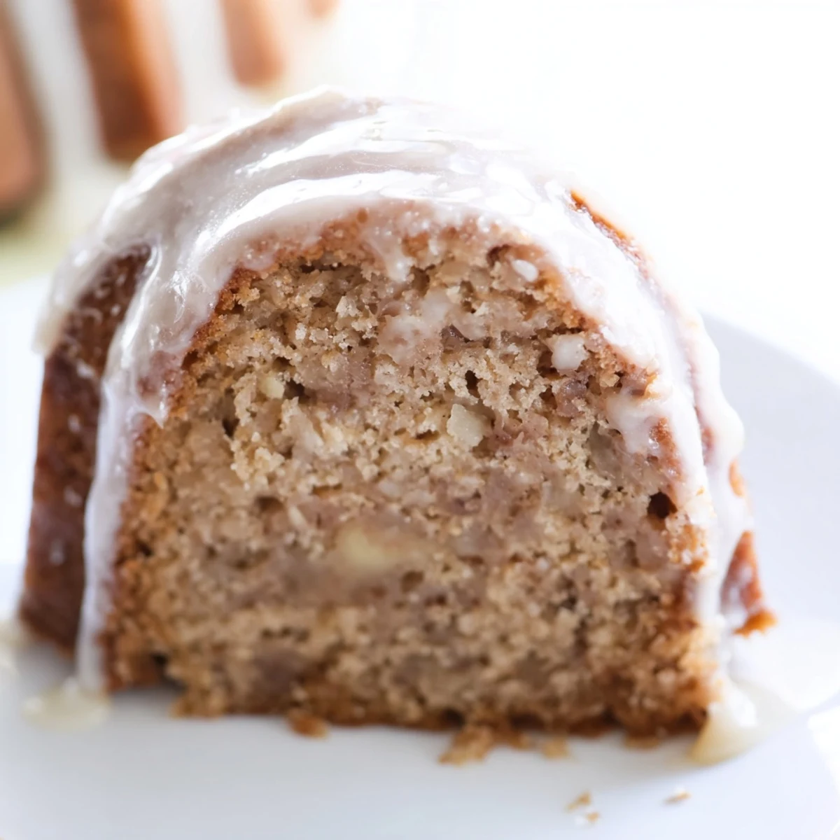 Moist Spiced Apple Cider Bundt Cake with a golden crust and glossy glaze, ideal for autumn dessert tables.