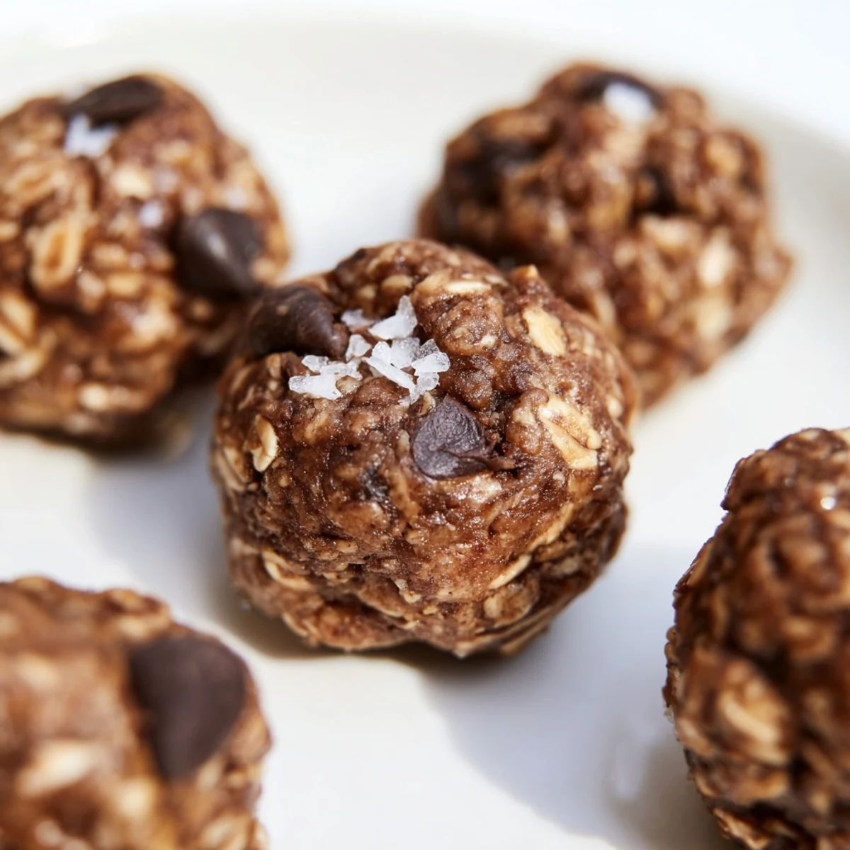 A close-up of Chocolate Peanut Butter Energy Balls highlights oats, seeds, and melted chocolate chips.