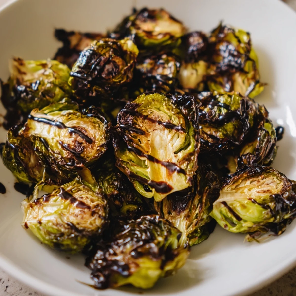 A close-up of roasted Brussels sprouts with balsamic glaze, showing crispy edges and a glossy, caramelized finish.  