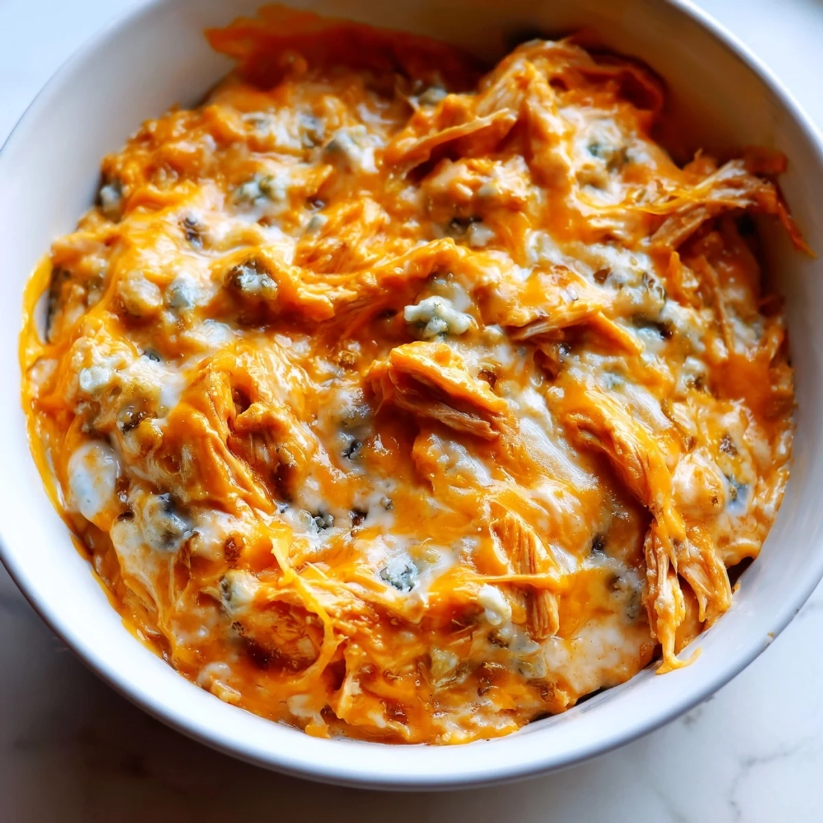 Golden, bubbly Buffalo Chicken Dip with celery sticks and chips ready for a game-day spread.  
