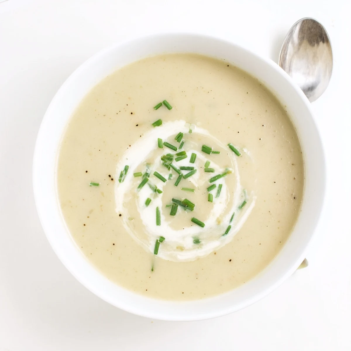 Creamy potato leek soup with chives garnished with fresh herbs in a rustic bowl.  