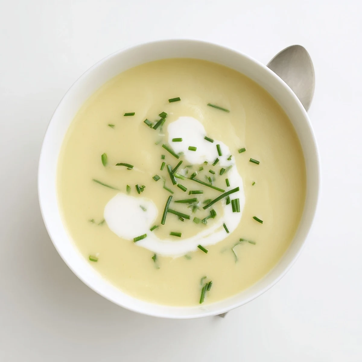 A bowl of creamy potato leek soup with chives and a swirl of cream.  