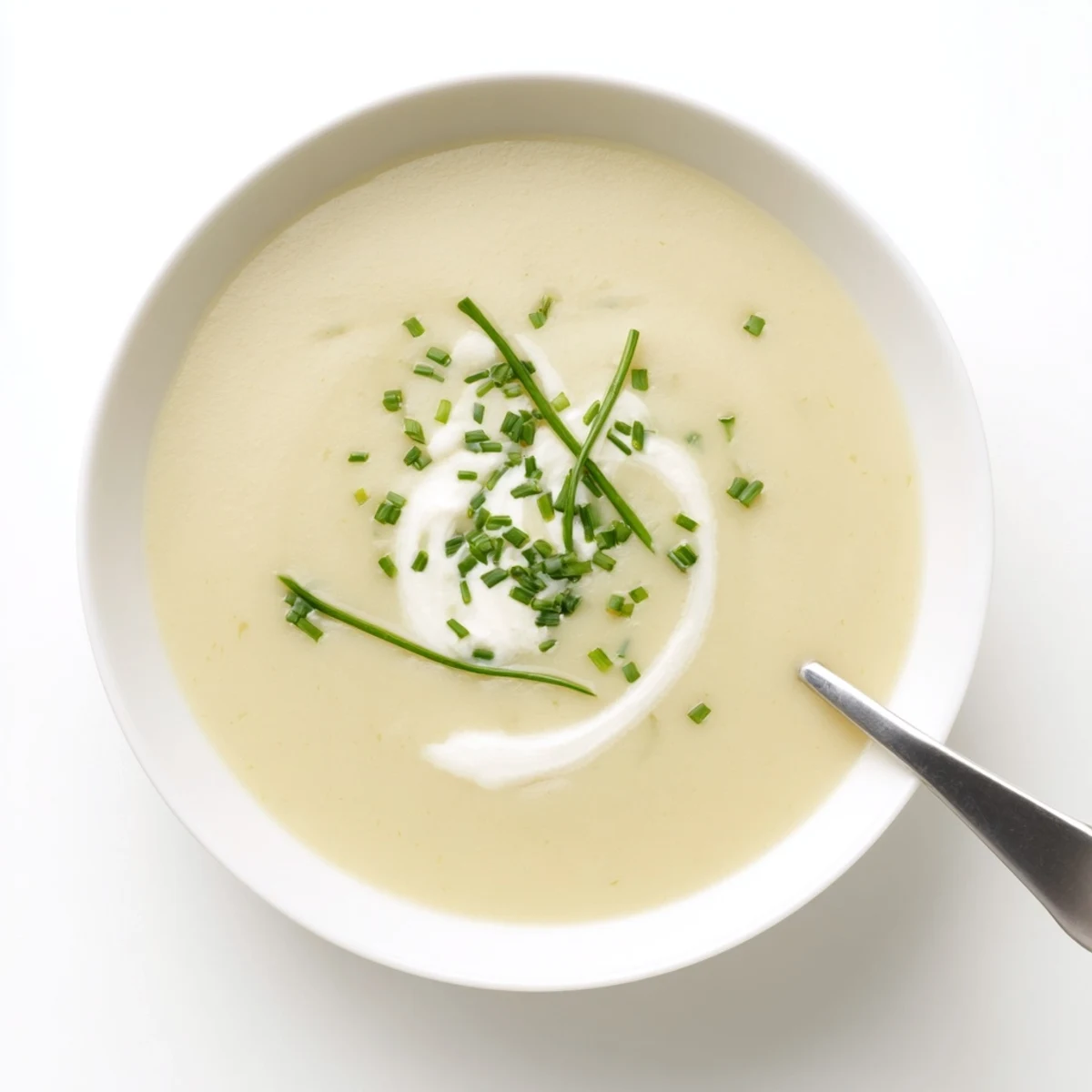 Steaming creamy potato leek soup with chives in a white bowl, perfect cozy dinner.