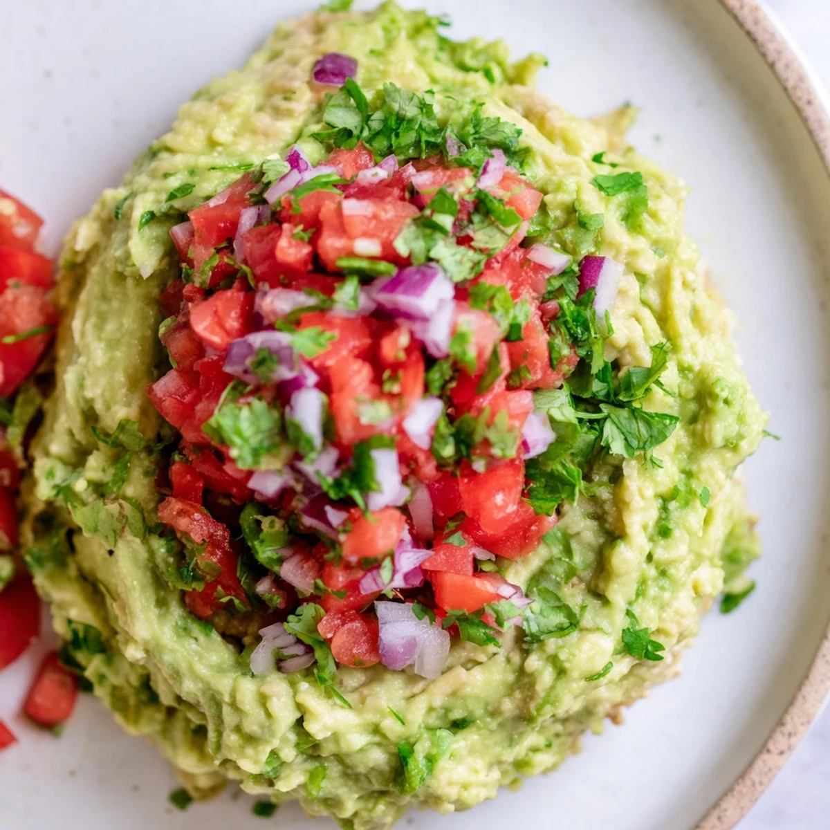 A vibrant bowl of homemade guacamole with fresh pico de gallo, garnished with cilantro and lime wedges for an extra zesty touch.
