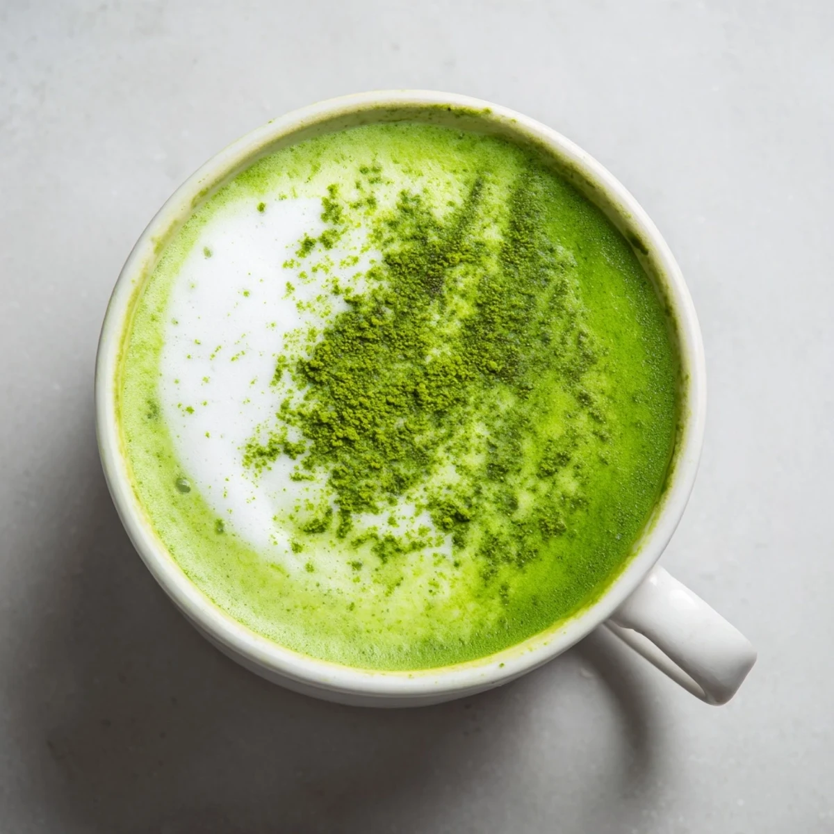 Creamy green matcha latte with oat milk is frothy and vibrant, served in a ceramic mug for a morning energy boost.