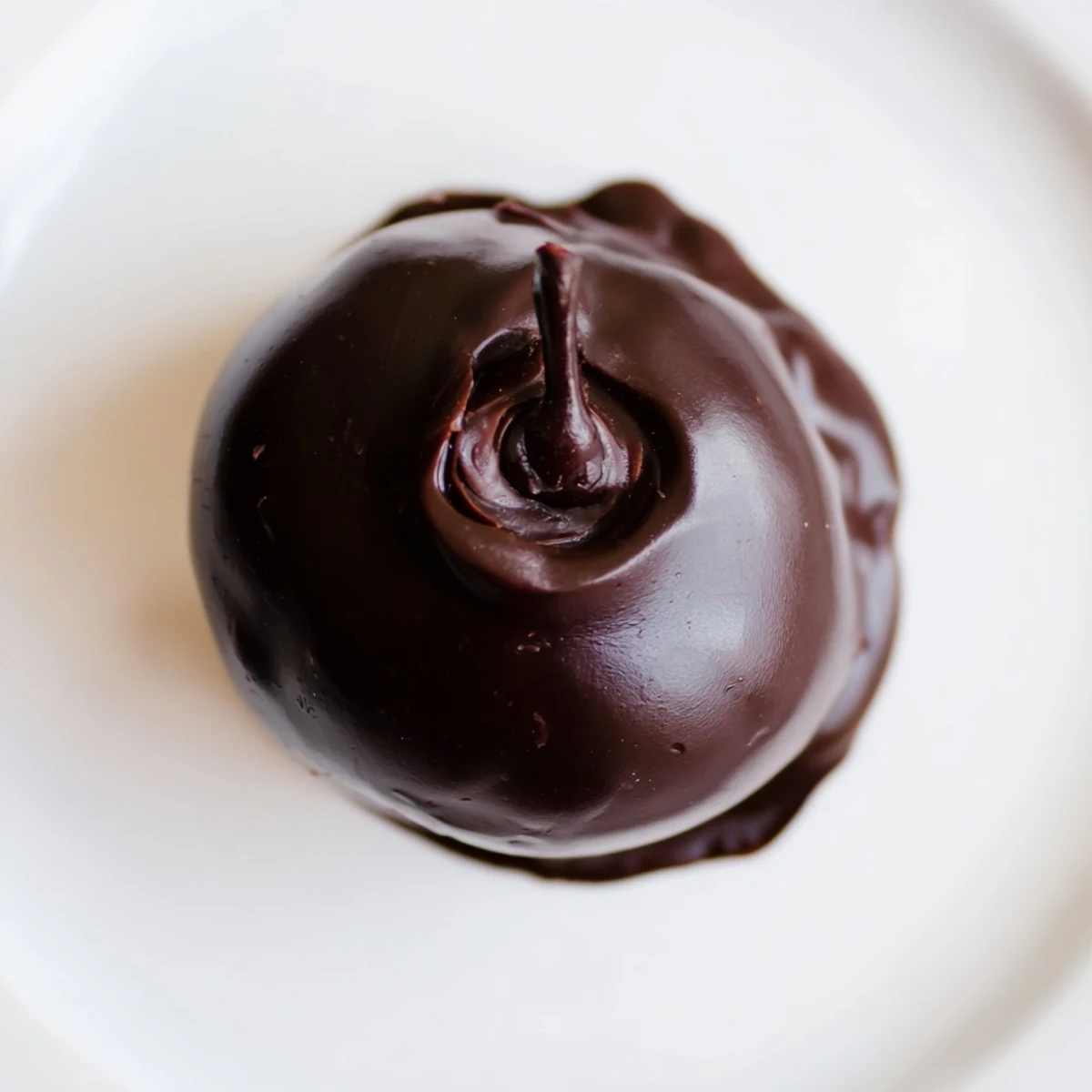 Hand-dipped chocolate covered cherries with stems, resting on a cooling rack with a rich, glossy chocolate finish.