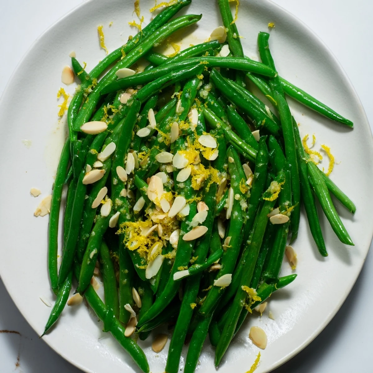 Heaped on a platter, Green Beans with Toasted Almonds and Lemon glisten beside roasted chicken for a festive side.