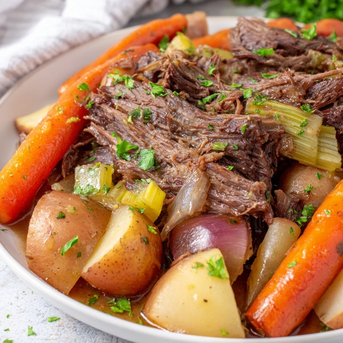 Tender beef pot roast with carrots parsnips and onions slow cooked until fork tender served in rustic dish.