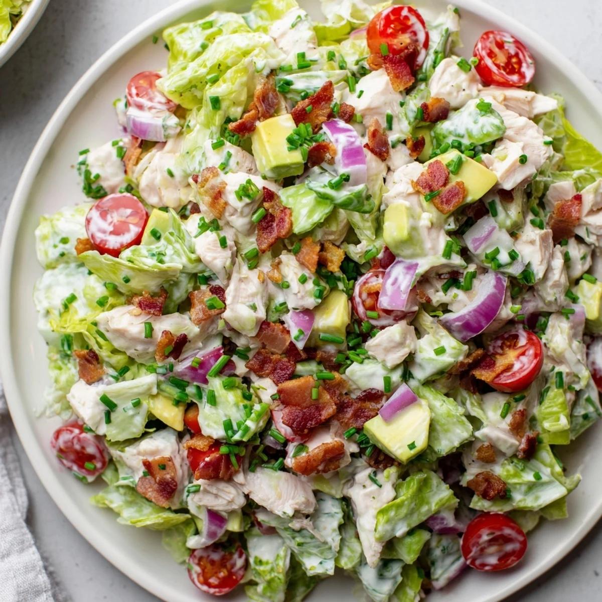 Serving suggestion for BLT Chicken Salad: present it chilled in a white bowl, highlighting crunchy lettuce and ripe avocado next to warm chicken.