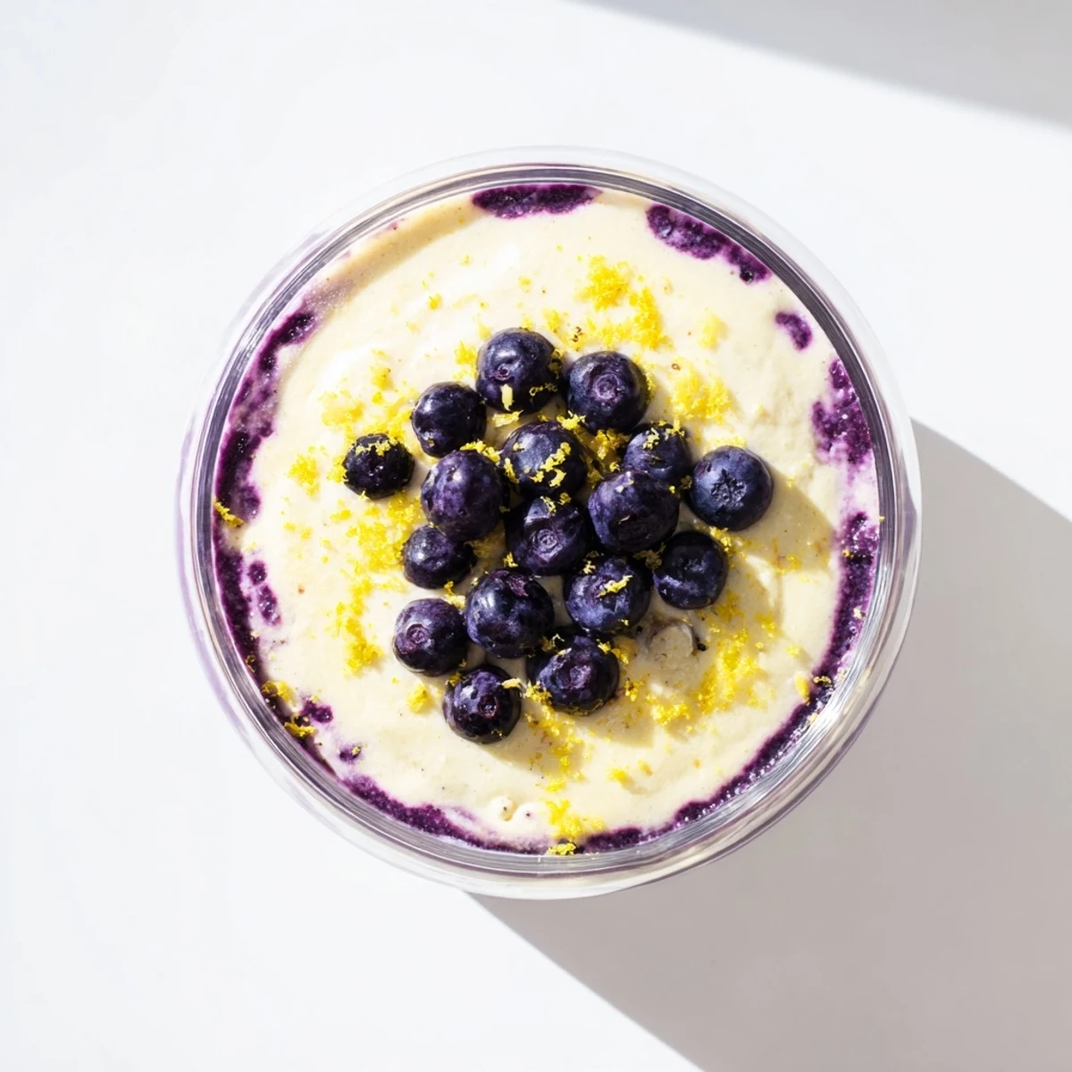 Glass dessert cup featuring Lemon Blueberry Mousse layered with vibrant purple compote and topped with fresh mint.