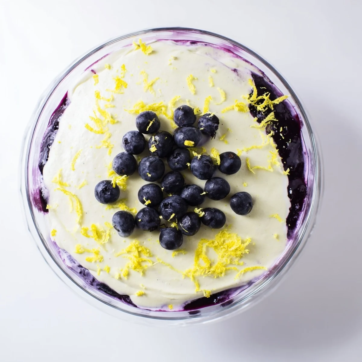 Clear glass holding a fluffy Lemon Blueberry Mousse garnished with lemon zest and plump fresh blueberries on top.