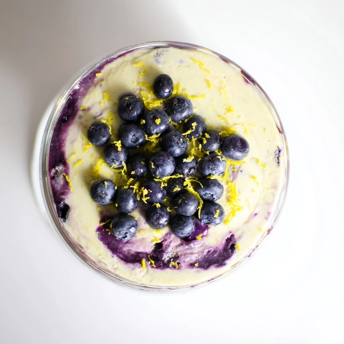 A single serving of chilled Lemon Blueberry Mousse with smooth lemon custard and a sweet blueberry sauce swirl.