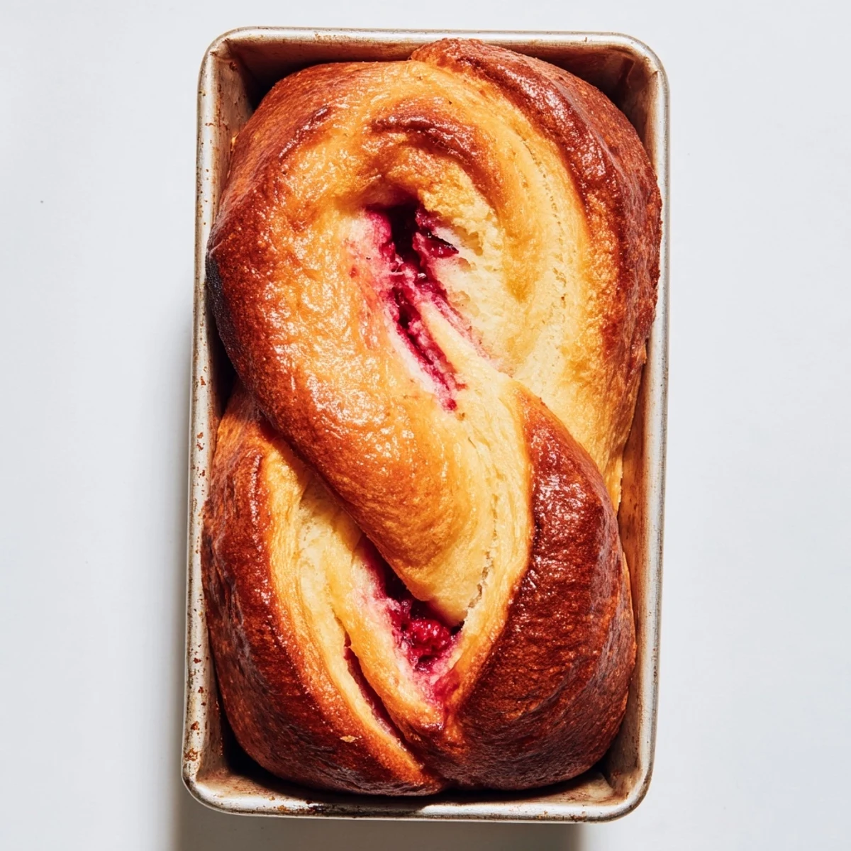 A close-up of Raspberry Swirl Brioche Loaf showing flaky buttery layers and tangy raspberry filling, perfect for brunch or an afternoon coffee treat.