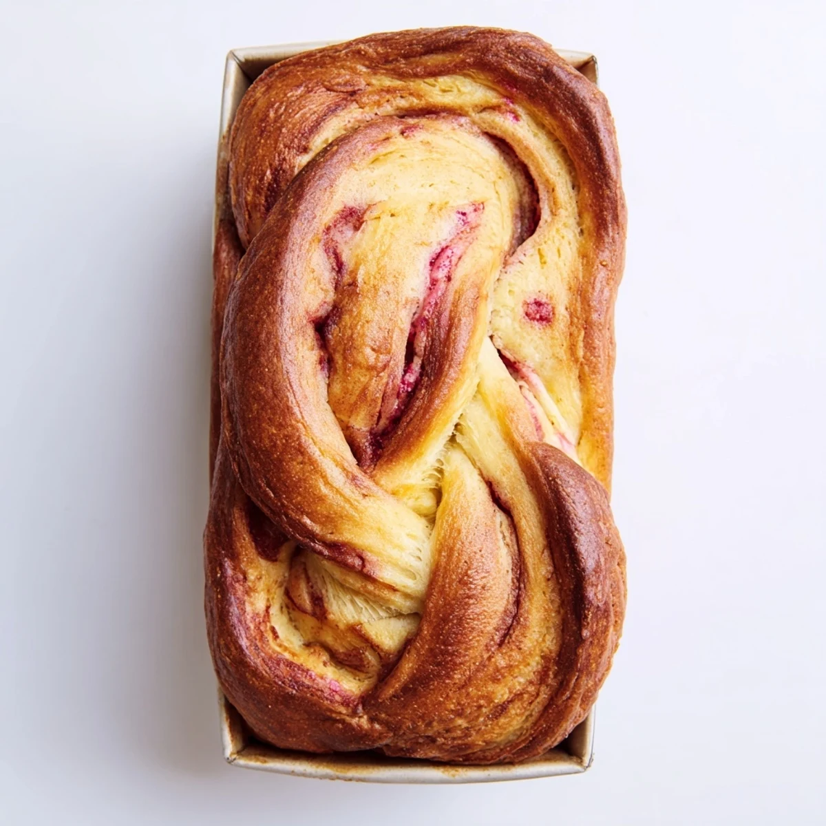 Raspberry Swirl Brioche Loaf on a rustic wooden board with fresh raspberries and a pat of butter, highlighting its soft texture and sweet aroma.