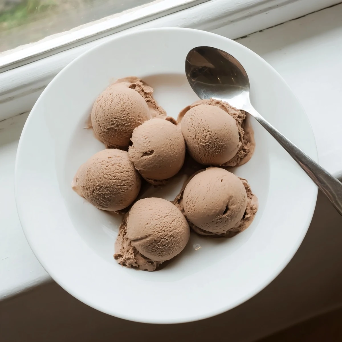 Vietnamese Coffee Ice Cream reveals a velvety beige custard texture studded with rich espresso swirls in a rustic ceramic dish.  