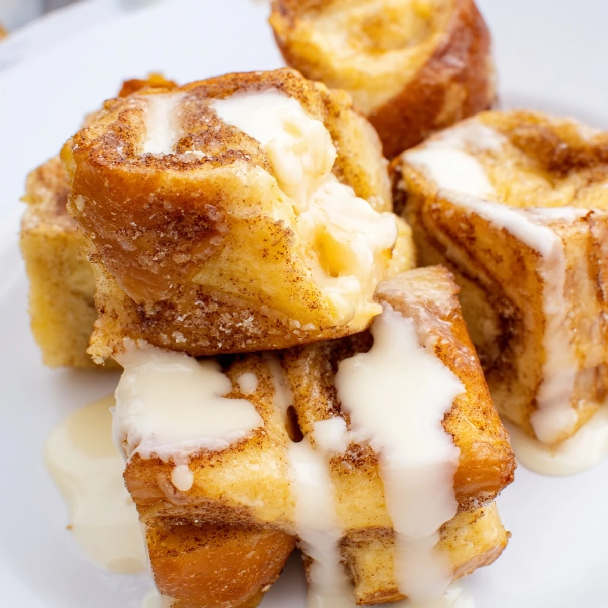 Steamy Cinnamon Roll French Toast Bites sizzle in a skillet, ready for a drizzle of maple syrup and butter.