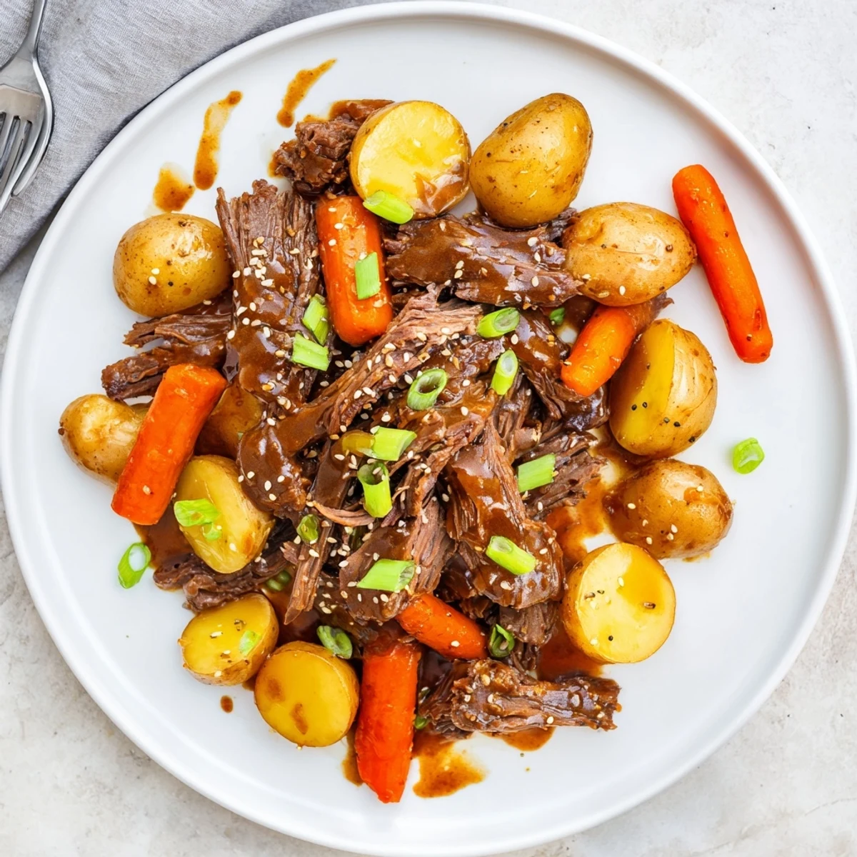 Shredded Slow Cooker Korean Beef Pot Roast drizzled with glossy soy garlic gravy over steamed rice.