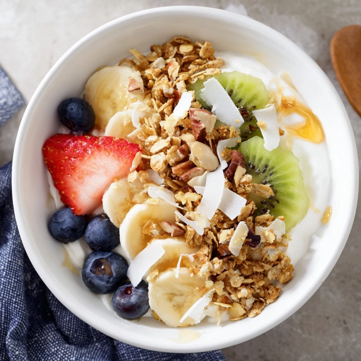 Freshly sliced banana and strawberries top a creamy Greek yogurt base with crunchy granola in this healthy breakfast bowl.