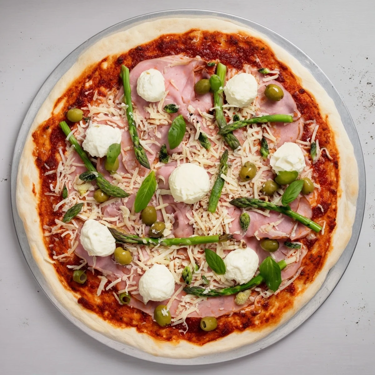Golden-crust Ham, Olive, Asparagus, and Ricotta Pizza topped with smoky ham, briny olives, tender asparagus, and creamy dollops of ricotta cheese.  