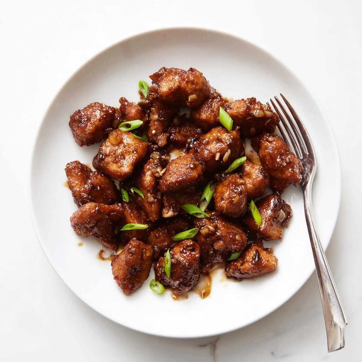 Tender pieces of Mongolian chicken coated in a thick caramelized sauce served over fluffy white steamed rice