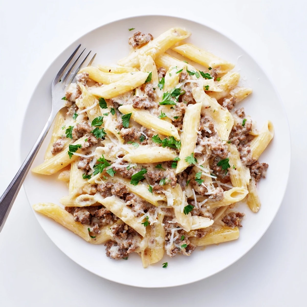 Steaming bowl of al dente pasta coated in rich Parmesan cream sauce with ground beef