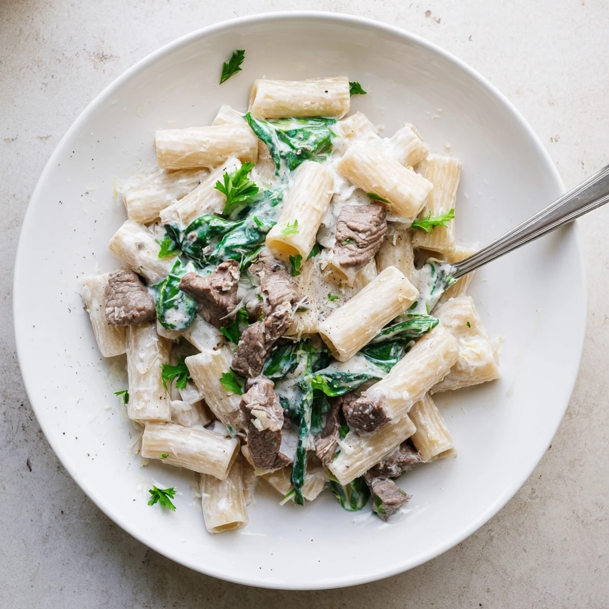 Close up of high protein beef pasta with spinach in a rich creamy sauce on a plate