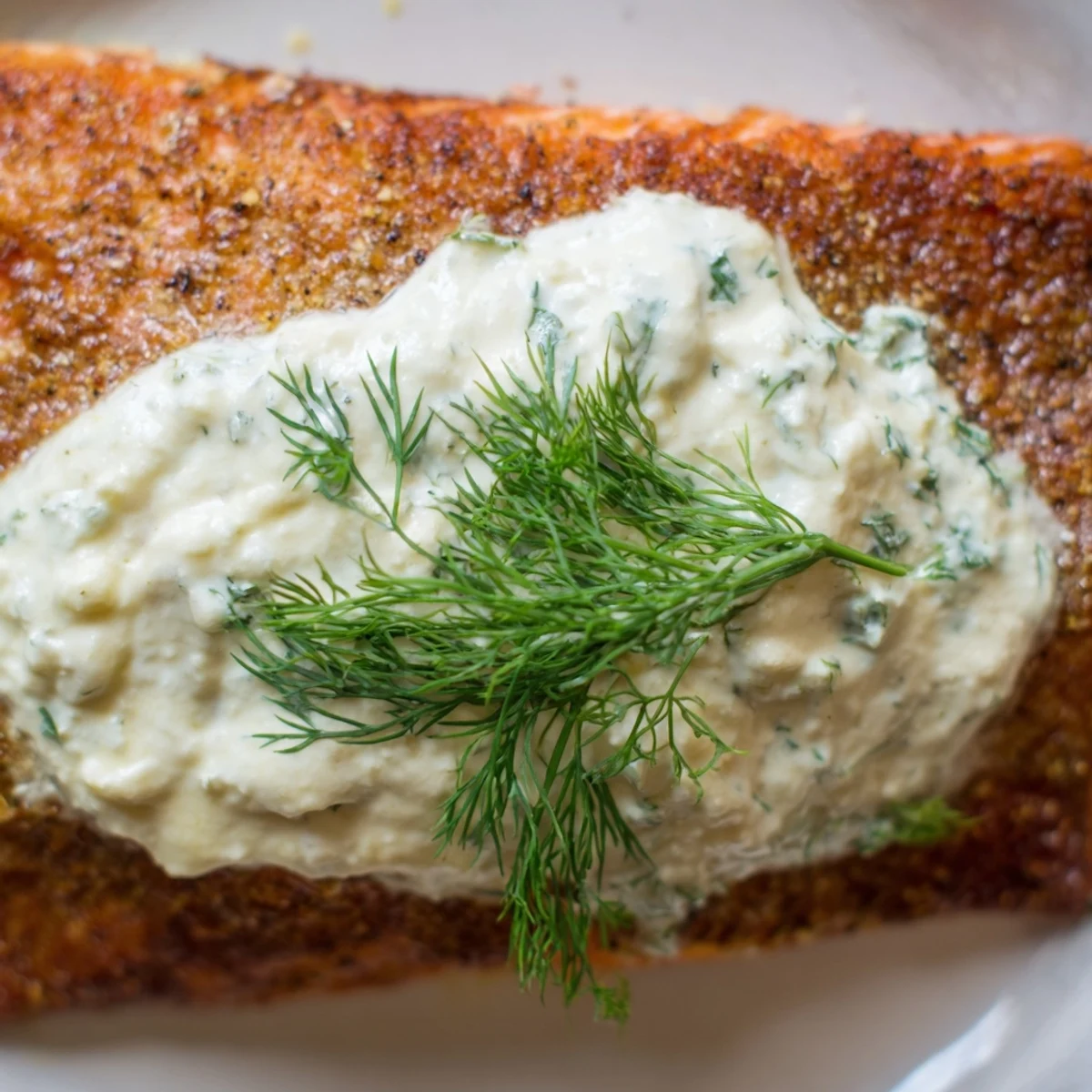 Golden roasted Mediterranean salmon fillets topped with creamy lemon dill yogurt sauce and fresh dill sprigs