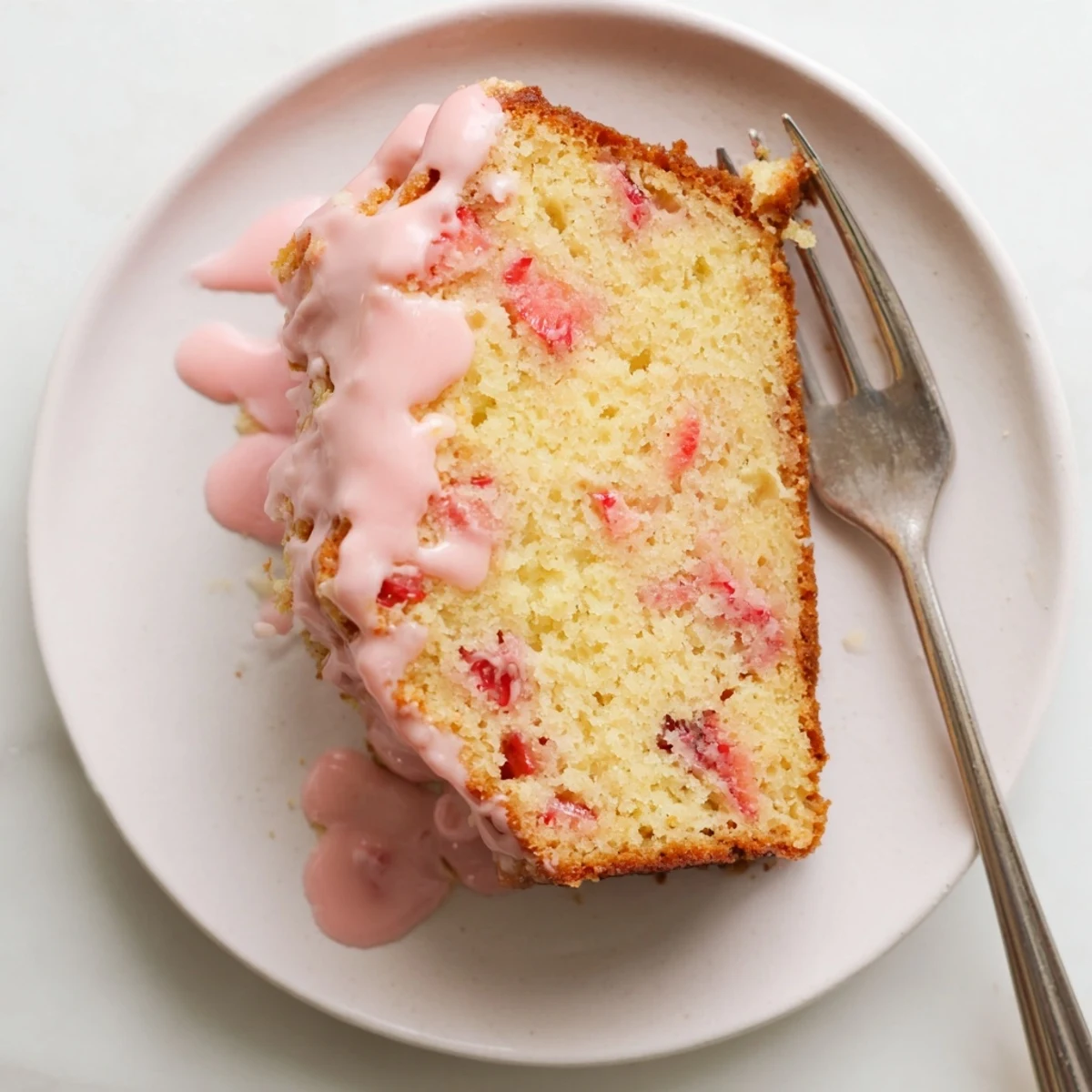 Homemade strawberry pound cake with red fruit pieces and glossy glaze ready for serving