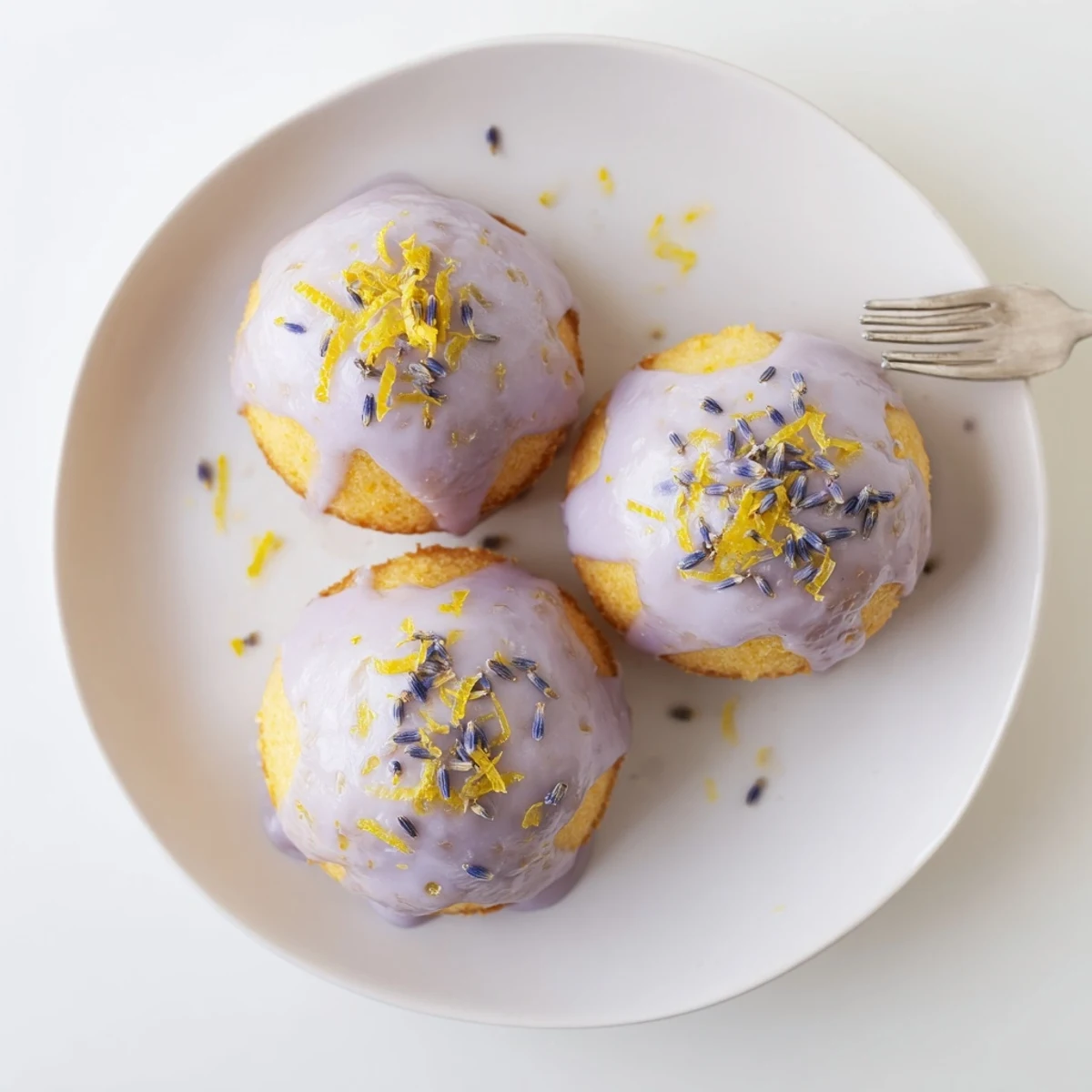 Tender bite-sized lemon cakes glazed with creamy lavender icing on a white serving plate