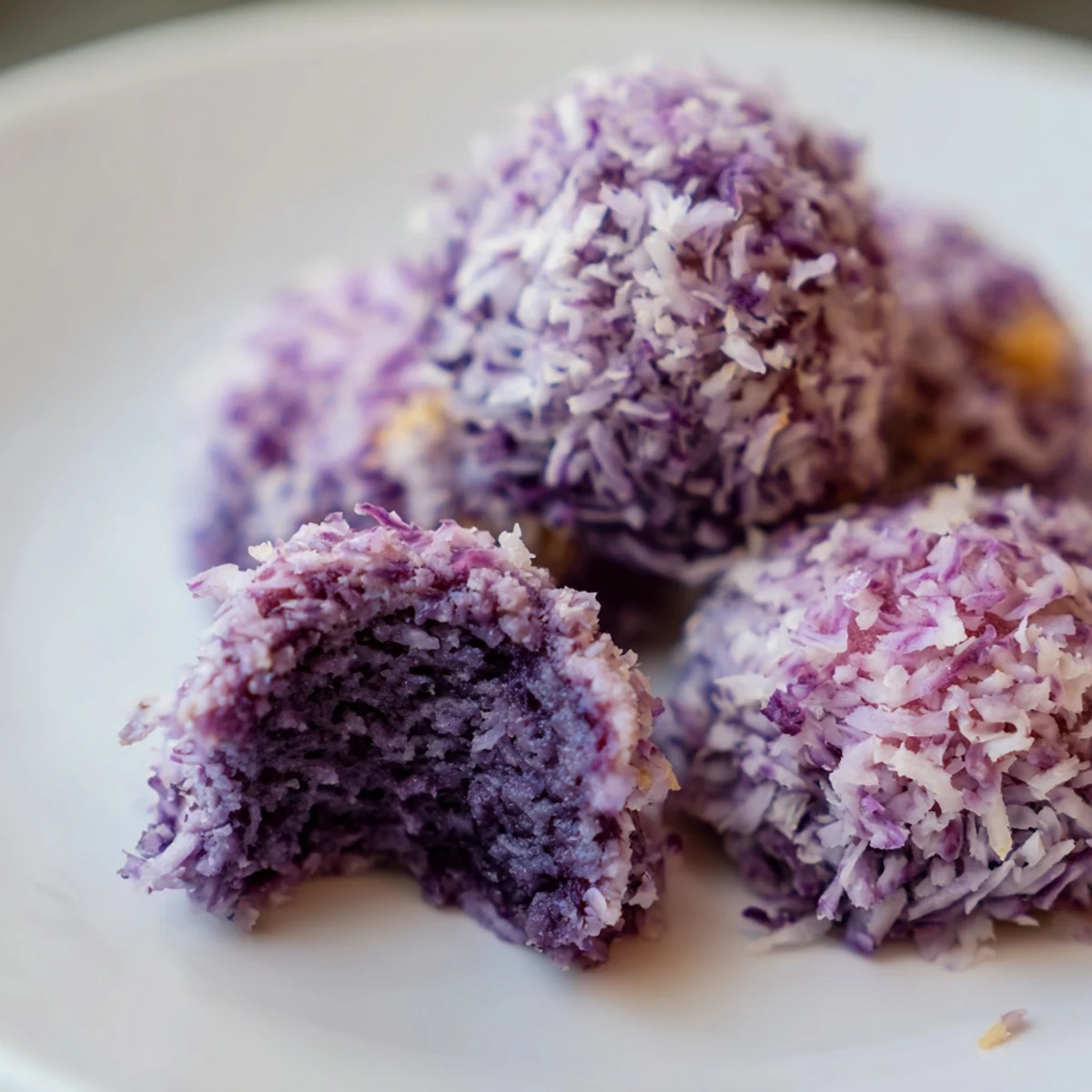 Golden coconut ube besito cookies with vibrant purple centers and snowy white coconut coating