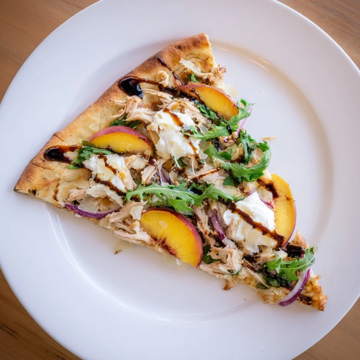 Summer pizza featuring juicy peaches, chicken, and creamy ricotta with peppery arugula topping