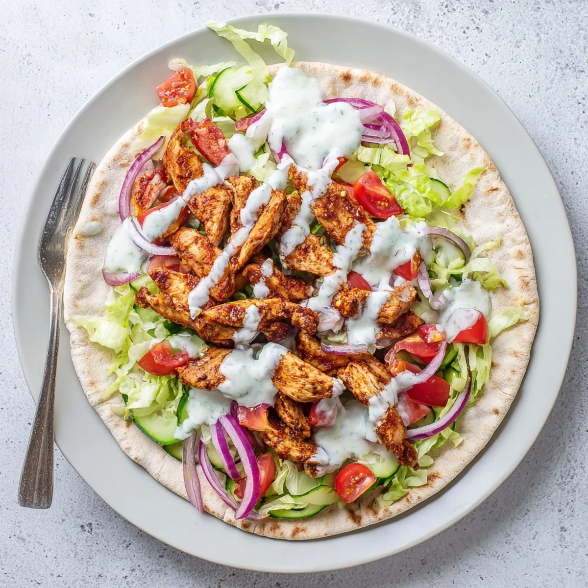 Sliced chicken shawarma seasoned with aromatic spices served over crisp lettuce and tomatoes in flatbread