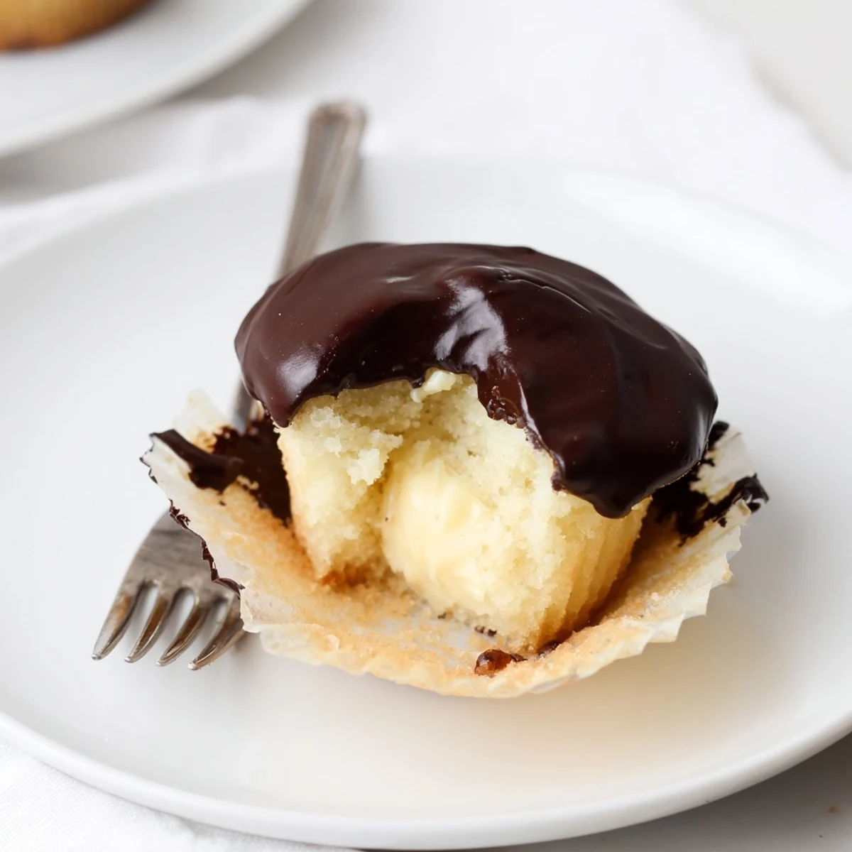 Golden Boston cream pie cupcakes topped with glossy chocolate ganache dripping down the sides