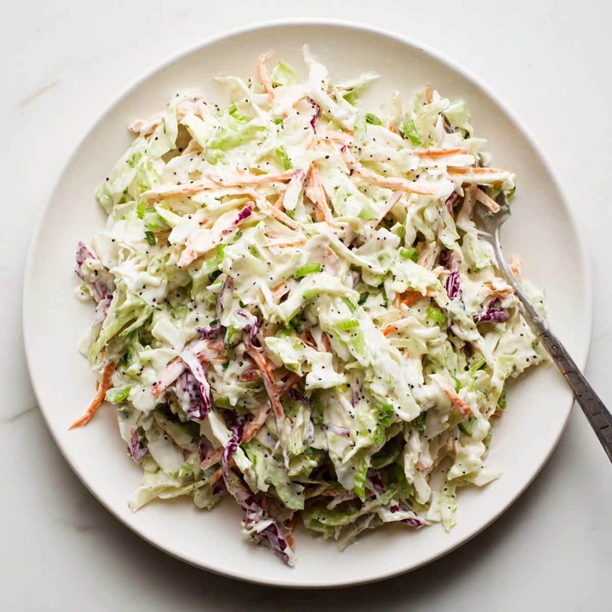 Colorful bowl of easy creamy coleslaw with vibrant cabbage and carrot coated in tangy homemade dressing