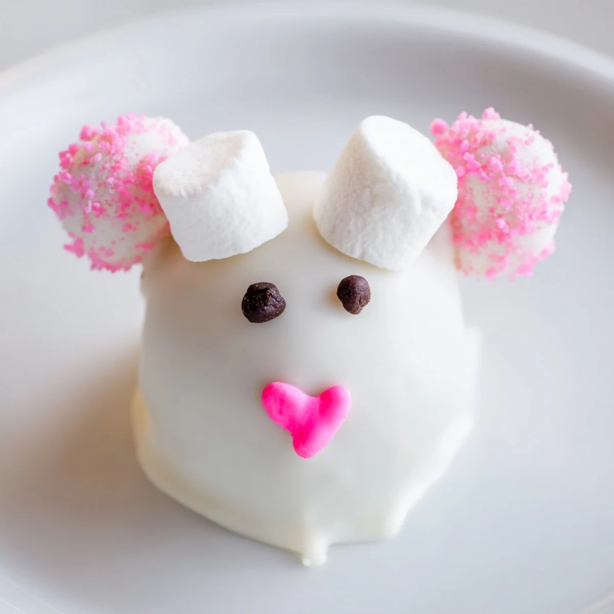 White chocolate dipped Bunny Oreo Balls with pink marshmallow ears and chocolate chip eyes on a white plate