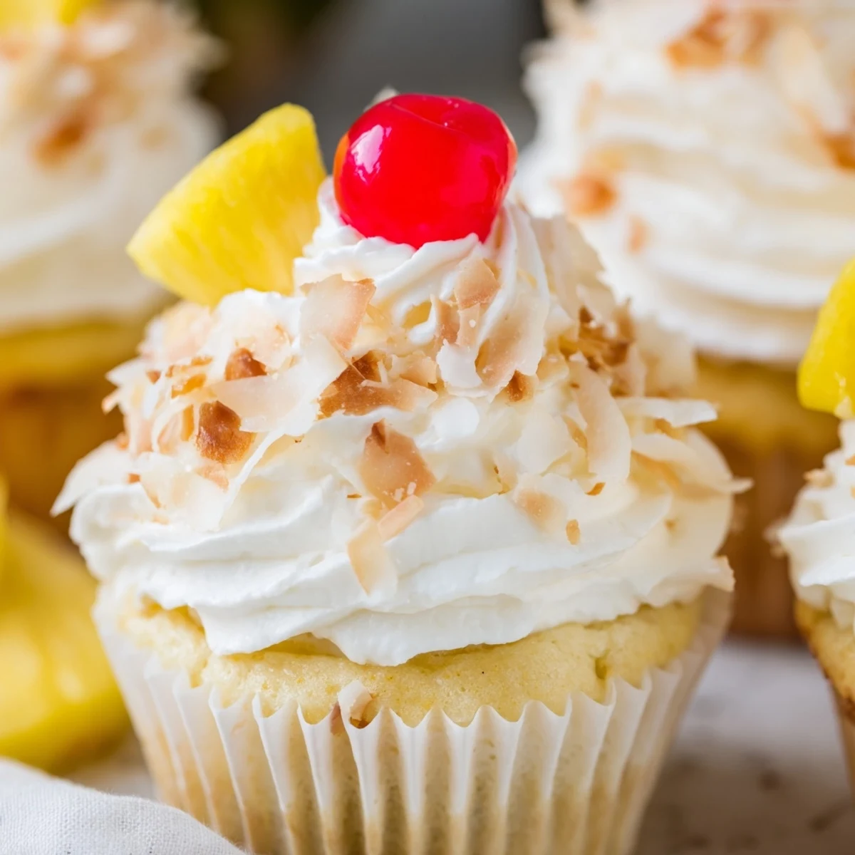Tropical Pina Colada cupcakes featuring pineapple coconut cake piled high with creamy buttercream and finished with sweet shredded coconut