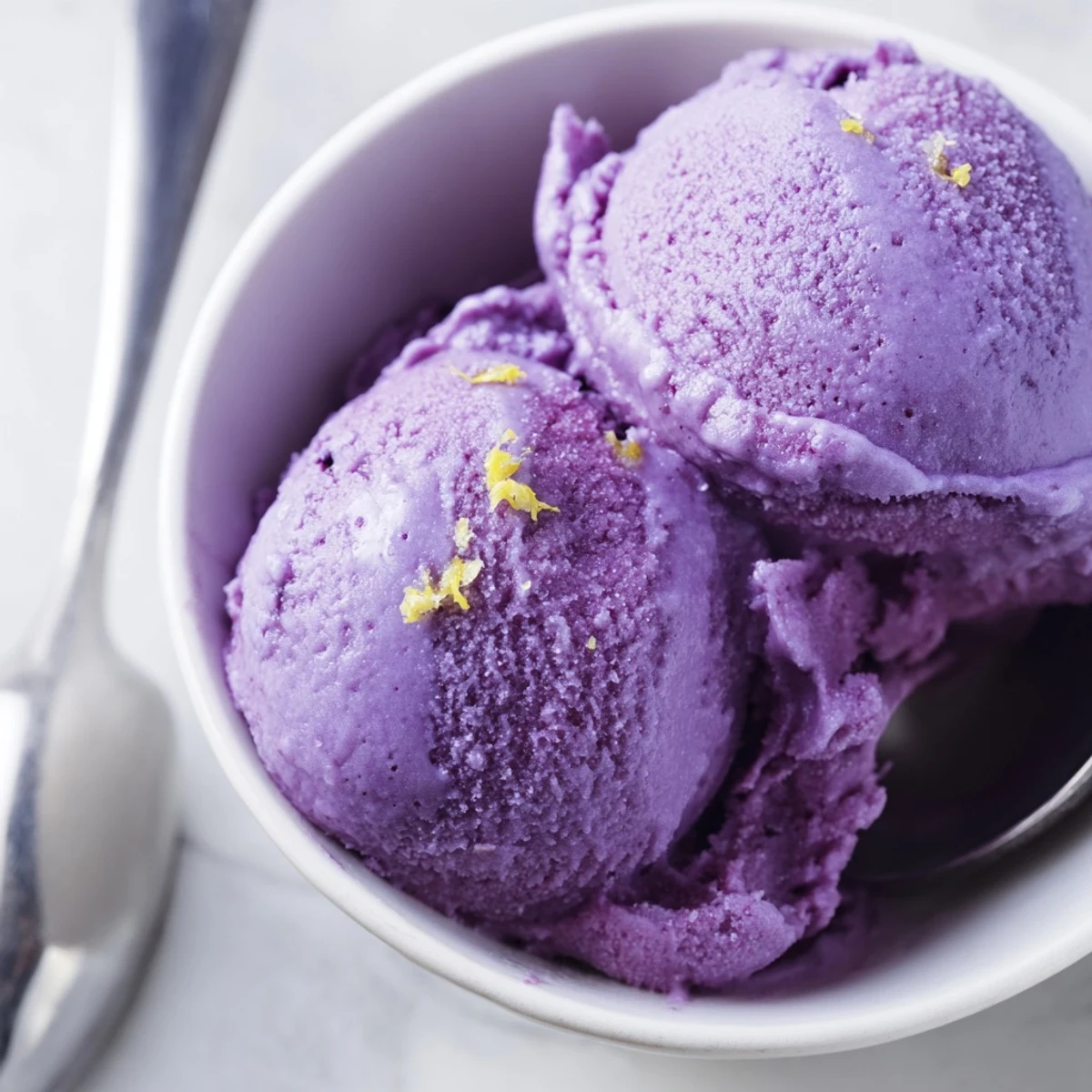 Vibrant purple no churn blueberry lemon sorbet scooped into a chilled glass bowl with fresh mint garnish