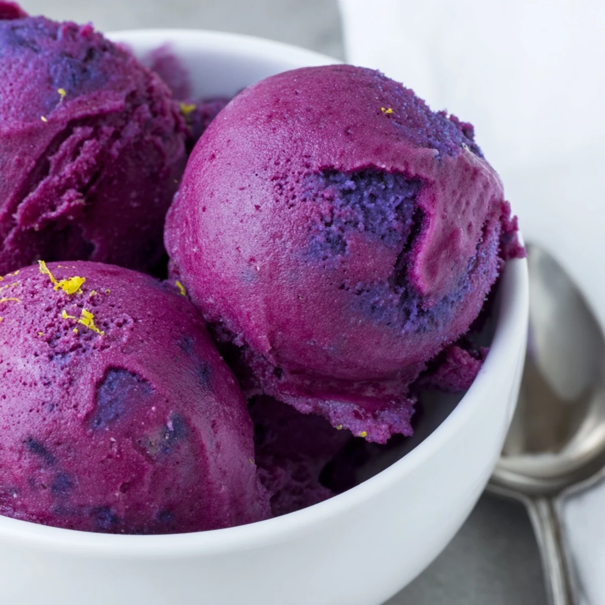 Homemade no churn blueberry lemon sorbet with bright purple hue served in vintage glass dishes with fresh blueberries