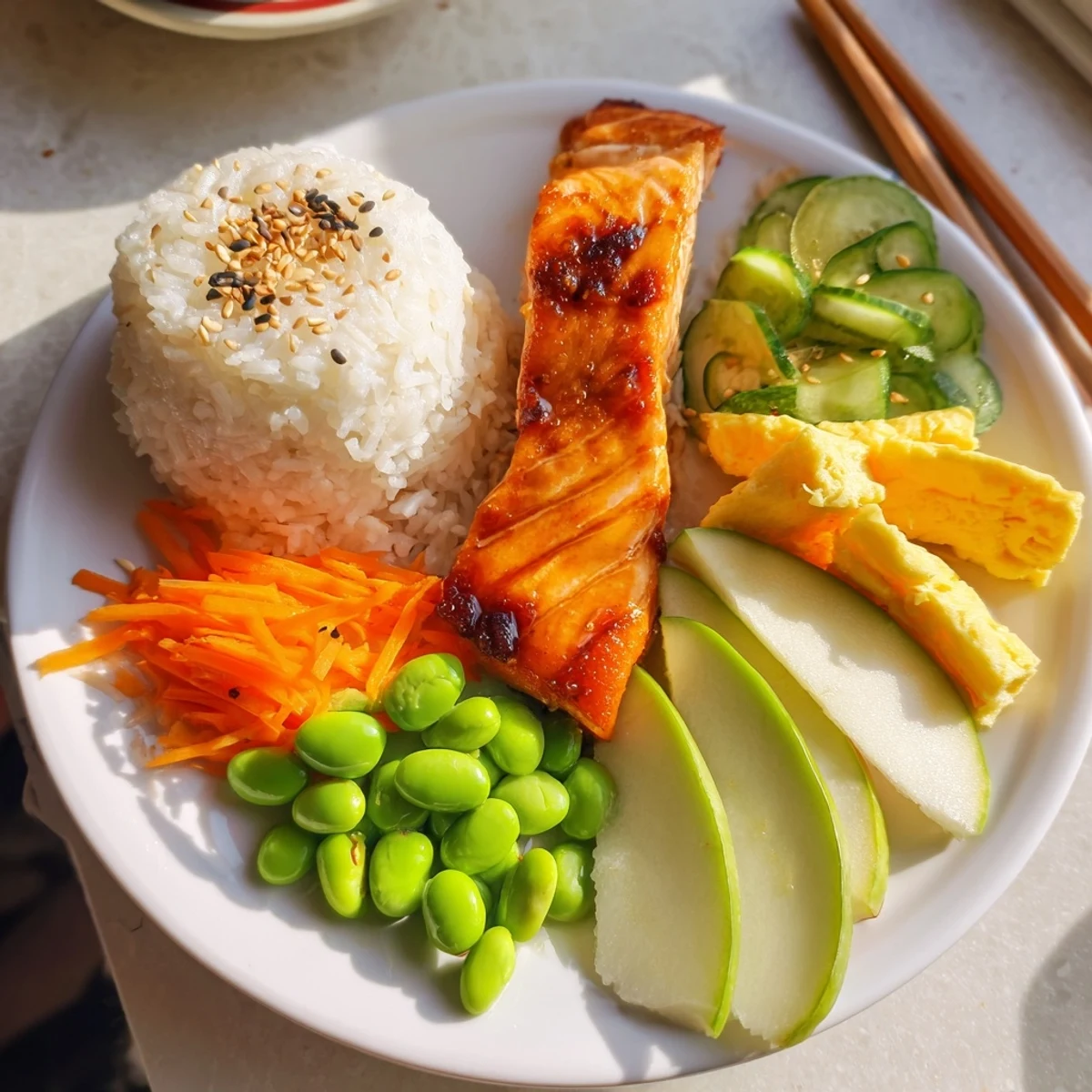Healthy Japanese Breakfast Bento Box featuring grilled salmon fillet alongside steamed rice and colorful pickled vegetables.