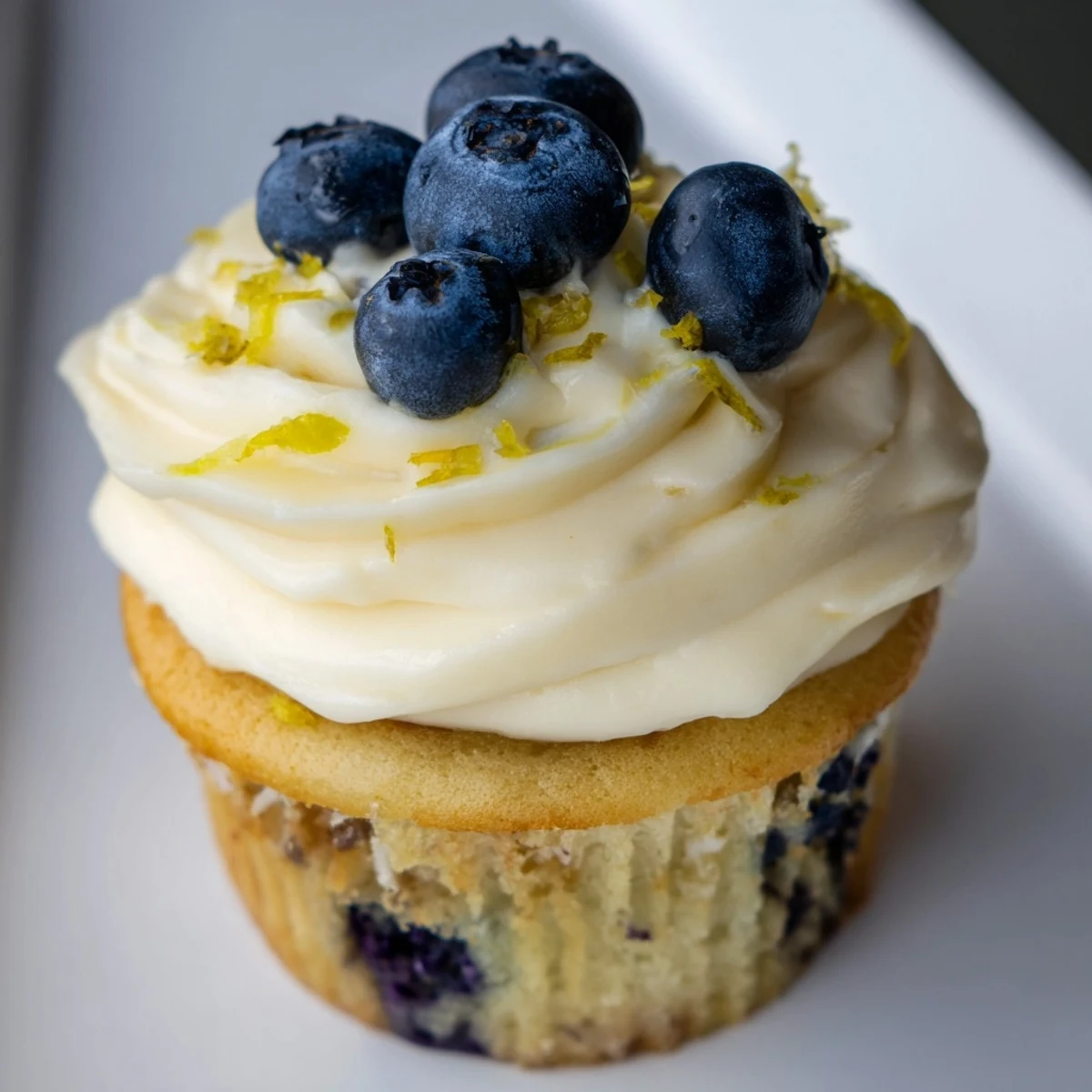 Fluffy homemade lemon blueberry cupcakes with swirled lemon frosting on a white serving plate