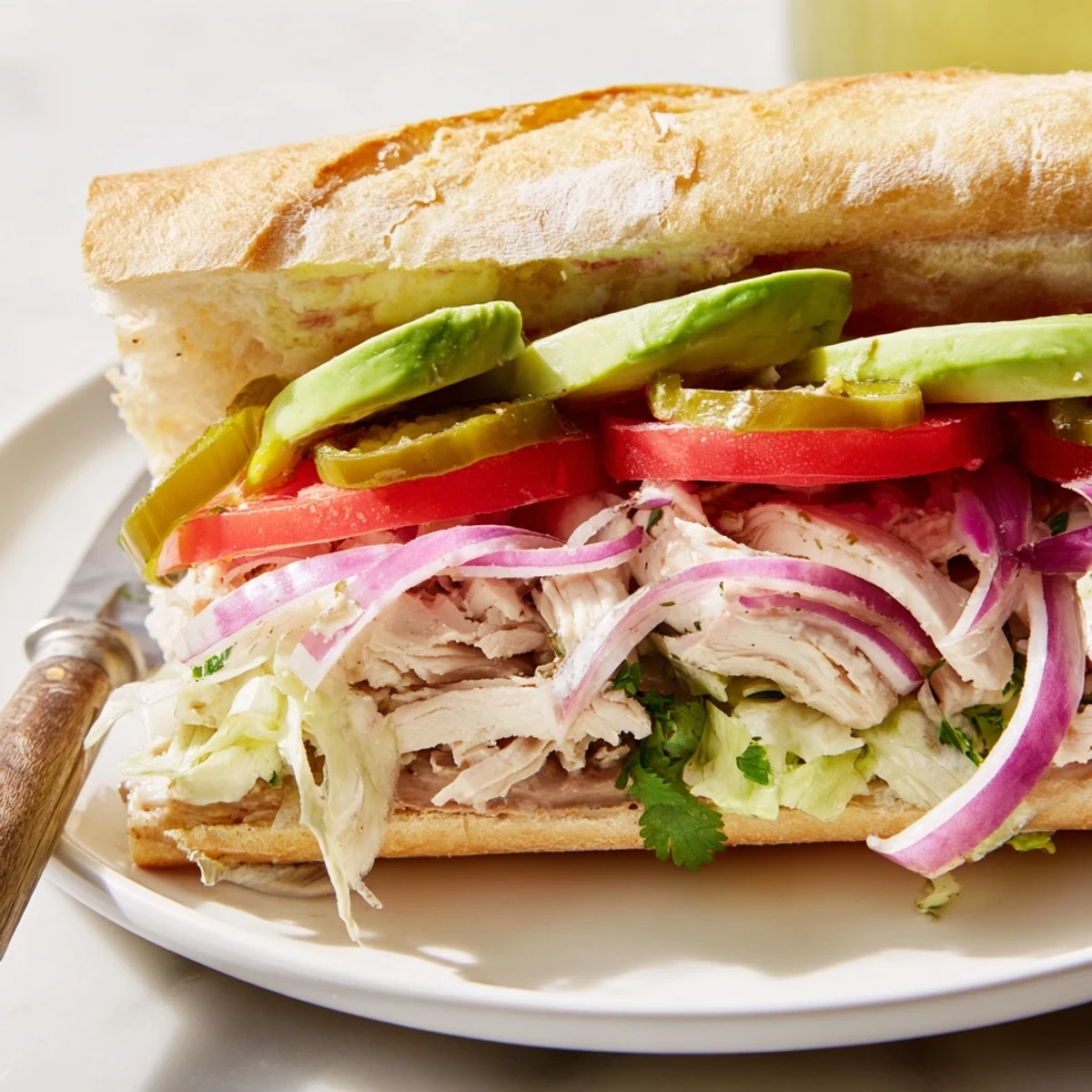 Mexican-style Chicken Torta Sandwich featuring spiced grilled chicken, fresh tomato, red onion, and zesty pickled jalapeños on soft bread